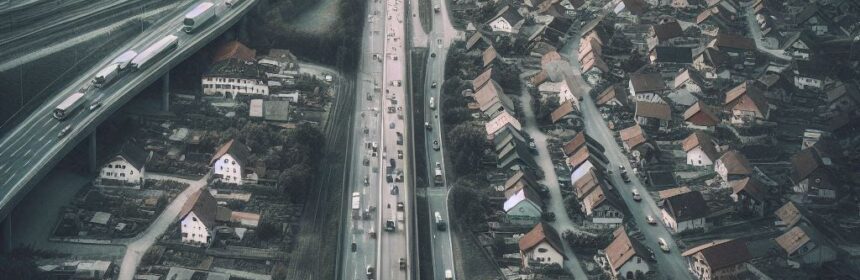 Dystopische Vogelperspektive auf ein Dorf mit Autobahn und viel Verkehr
